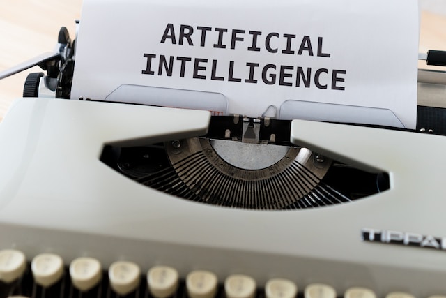 an old typewriter, with a white sheet of paper with the words Artificial intelligence written on it