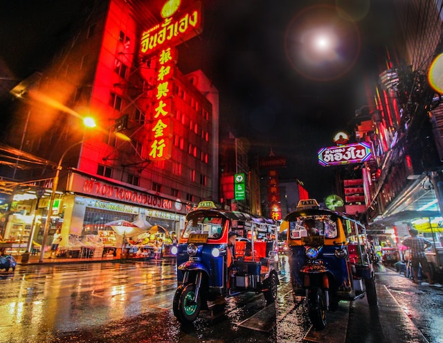 Street in Thailand at night with car traffic and neon signs