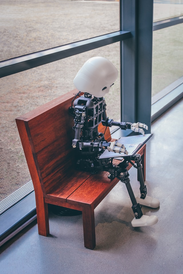 A robot sitting on a bench, reading a book