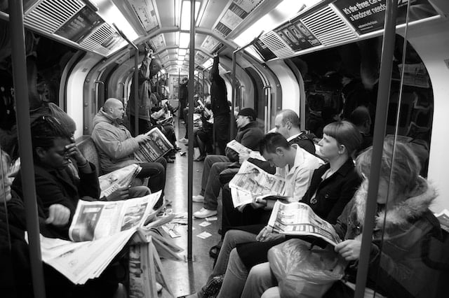 people in the subway reading newspapers