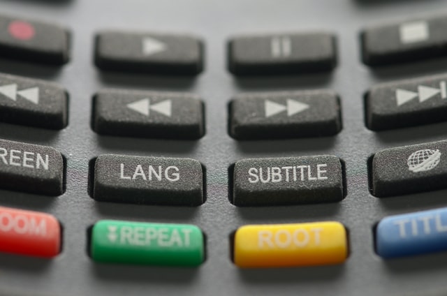 gray TV remote with red subtitle button